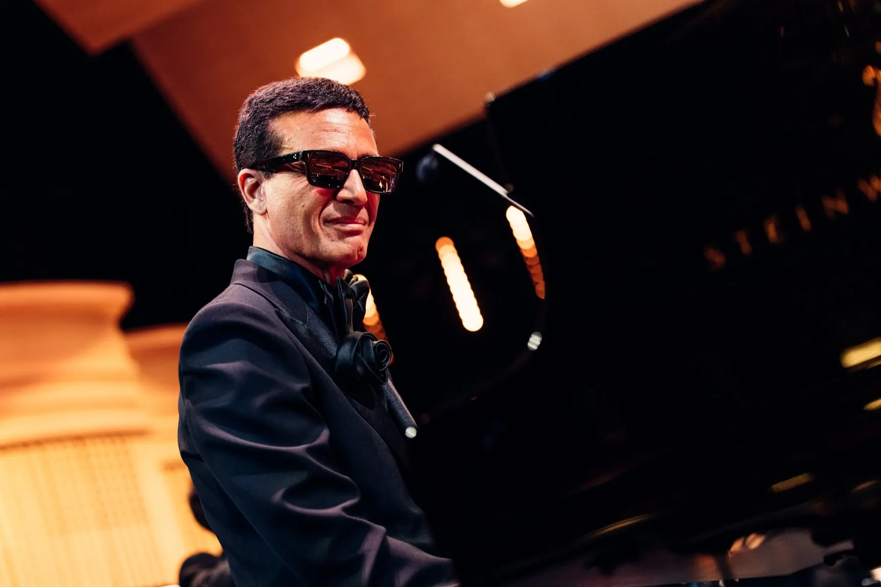 Omar Harfouch smiling behind the piano